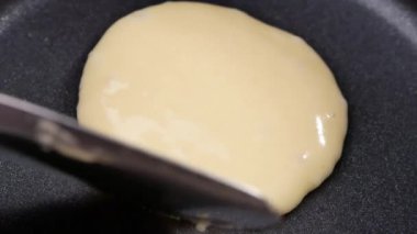 Yapışmayan bir tavada ev yapımı krep lezzetli bir kahvaltı yemeği pişirir. Sıcak tavada krep devirmek için tong kullanan kadın eller..