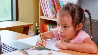 Evdeki çevrimiçi dersi sırasında ödev matematiği okuyan küçük tatlı bir kız öğrenci. Koronavirüs salgını sırasında sosyal mesafeler. Çevrimiçi eğitim kavramı ya da evde öğrenim.