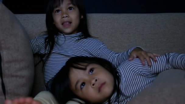 저녁늦게 거실에 소파에 텔레비전에서 만화를 귀여운 어린이들이 아시아 자매들은 집에서 — 비디오