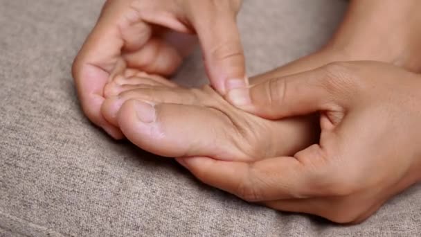 女性抱紧疼痛的脚 按摩她的脚趾以减轻疼痛 大脚趾边缘的浮肿会导致畸形 Hallux Valgus 妇女健康概念 — 图库视频影像