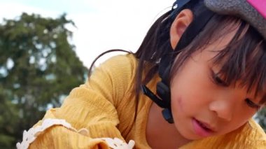 Kasklı iki küçük kız kardeş güneşli bir yaz gününde parkta kumla oynuyorlar, bisiklet antrenmanından sonra mola veriyorlar. hayal gücünü ve keşfi geliştir.