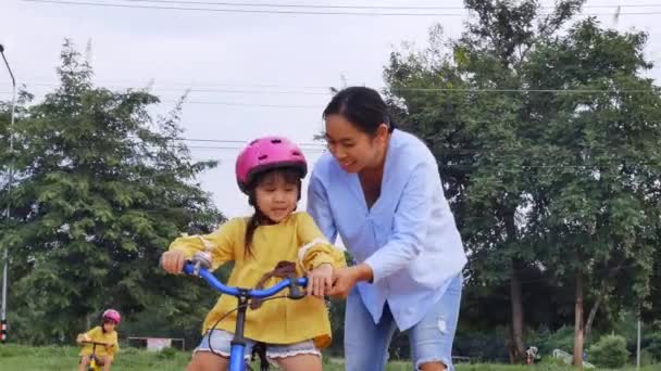 헬멧을 귀여운 소녀는 공원에서 엄마와 자전거타는 배웁니다 아이들을 스포츠 시절의 — 비디오
