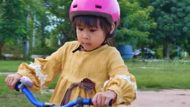 헬멧을 귀여운 소녀가 공원에서 자전거타기를 연습하고 있습니다 아이들을 스포츠 시절의 — 비디오