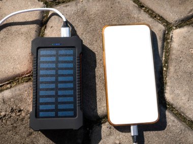 Güneş panelleri ile yeniden şarj edilebilir mobil güç paketi, yakın plan. Bir cep, tablet veya akıllı telefona bağlanıp şarj ediliyor.