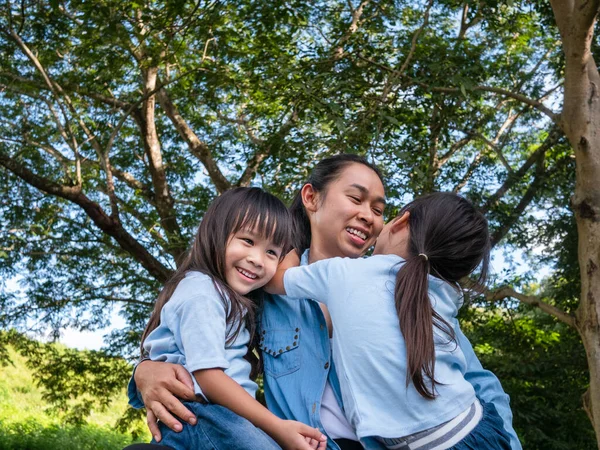 庭で暖かく晴れた夏の日にお母さんが笑って抱き合っている2人の兄弟の小さな女の子 若いです女の子とともに彼女の母親支出日で公園 — ストック写真