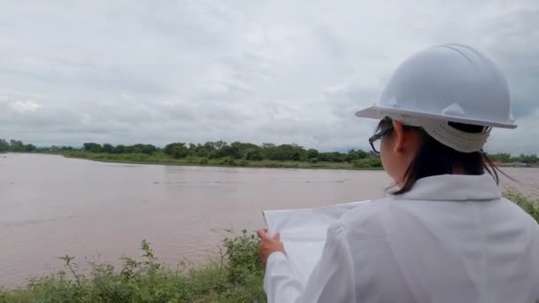 Женщина Инженер Держащая Руках Чертеж Прогуливается Вокруг Плотины Электрификации Реки — стоковое видео