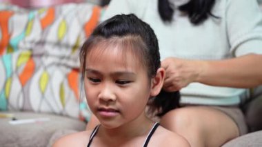 Bir annenin kızının saçını ördüğü sıcak ve samimi bir an. Küçük kız evinde gülümserken..