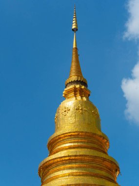 Tayland 'da açık mavi gökyüzünün altında parlayan altın pagoda stupa, Budist tapınağı mimarisini, dini, kültürü ve seyahat merkezini temsil ediyor..