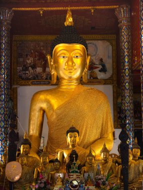Tayland tapınağındaki altın Buda heykeli Budizm, inanç, barış ve geleneksel Tayland kültürünü temsil eden küçük Buda resimleriyle çevrili..