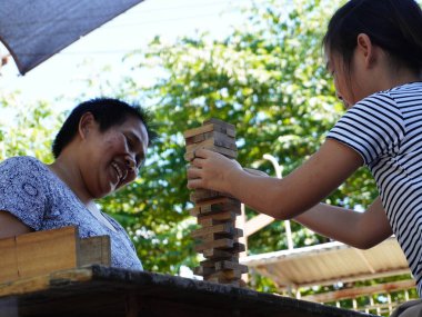 Bir anne ve kızın, Jenga 'nın tahta blok oyununu oynarken konsantre olup gülümsediği neşeli, yakın plan bir an..