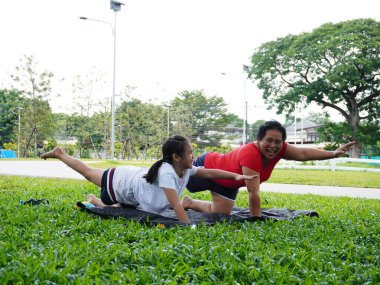 Bir anne ve kızı yoga yaparken ya da yeşil bir parkta siyah bir paspasın üzerinde esneme egzersizleri yaparken gösteren iki görüntü. sağlıklı yaşam tarzı ve aile zamanı.