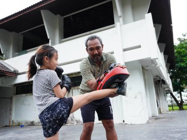 Baba-kız Muay Thai 'de ya da kickboks' ta antrenman yapıyor. Sahneler, ortak bir atletizm aktivitesi yoluyla dövüş sporları eğitimi, disiplin, fitness ve güçlü aile bağlarını vurguluyor..