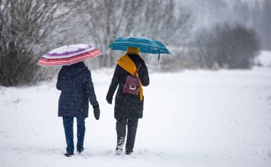 Şemsiyeli kadınlar kışın yürür, kar yağar