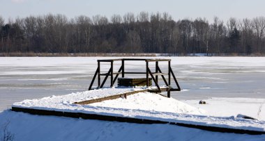 Karla kaplı donmuş bir nehirdeki ahşap iskele, Polonya 'da kış.