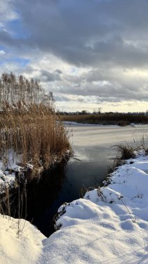 Kışın ağaçlarla kaplı donmuş nehir.