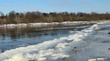 Kışın Narew Nehri 'nde, yüzen buz kütleleri yakındır. Nehir manzarası ve donmuş sahili fırçalayan dalgalı buz kütleleri.
