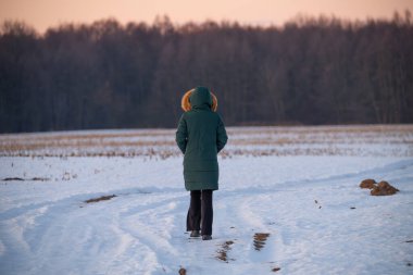 Karda yürüyen bir kız. Kız ormanda yürüyor..