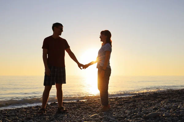 恋人たちは笑顔で 海辺の夕日の光の中でお互いを見ています 幸せな関係を — ストック写真