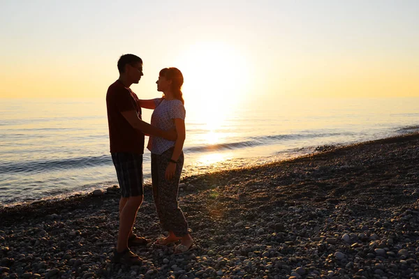 満足した男と女が近くに立って抱擁し 海のビーチで日没でお互いを見てください バレンタインデーの幸せな関係の概念 — ストック写真