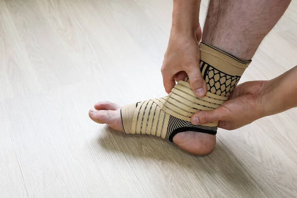 Human hands fix an elastic bandage sock to protect the ankle of the leg from sprains, close-up