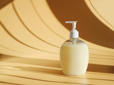 Krema arka planında kahve gölgeleri ve fotokopi alanı olan sıvı sabun.