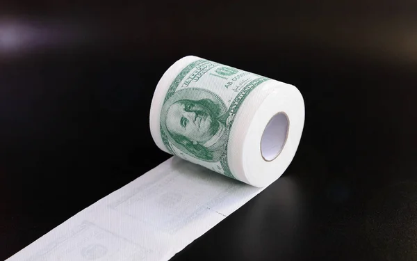 Roll of toilet paper in form of dollars, concept of deficit and inflation, on black background with copy space