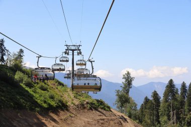 Krasnaya Polyana, Sochi, Rusya - 29 Ağustos 2020: Güneşli yaz gününde, insanlarla dolu açık tip bir teleferikli dağ manzarası