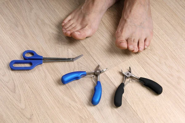 木地板上有切割钉子和男性脚的工具 特写镜头 — 图库照片