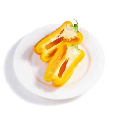 Beyaz tabakta iki yarım sarı dolmalık biber.