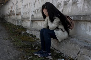 Depresyondaki genç kız yaşlı duvarın yanında oturuyor.. 