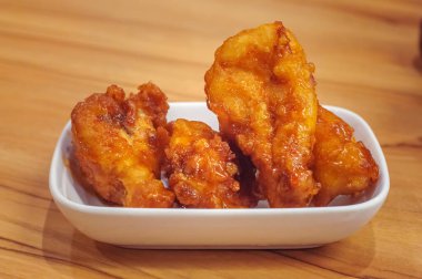 Kızarmış tavuk budu ahşap masada beyaz tabakta.