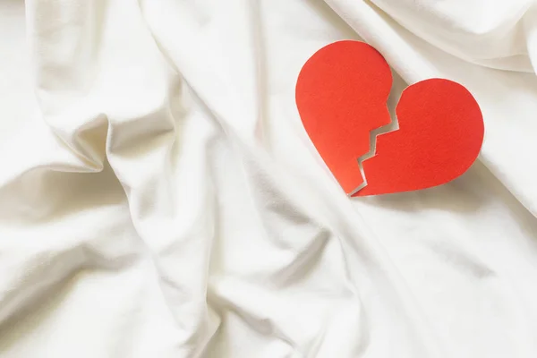 Разбитое красное сердце на белой ткани. концепция развода. — стоковое фото