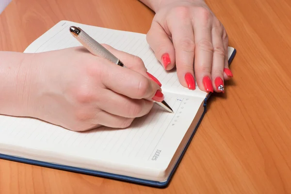 Female hands with manicure over pages of a notebook — Stock Photo, Image