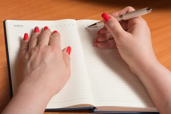 Female hands with manicure over pages of a notebook — Stock Photo, Image