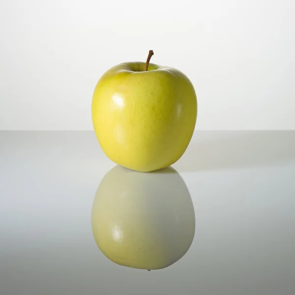 Manzana verde en una superficie con reflejo — Foto de Stock