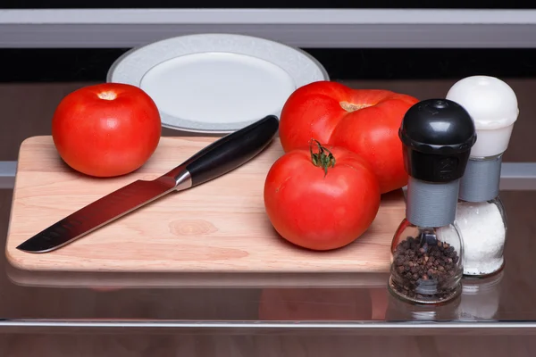Pomidory i nożem na stolnicy — Zdjęcie stockowe