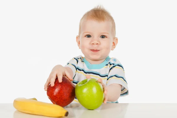 Petit garçon assis à table avec des fruits — Photo