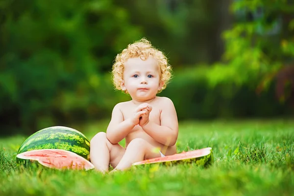 Child sitting on the grass with a watermelon — Stock Photo, Image