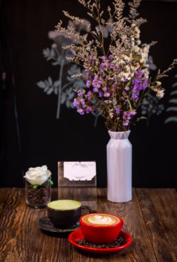 Kırmızı bardakta sıcak kapuçino kahve ve ahşap masada çay tabağı, rahatlama ve giriş metni görüntüsü