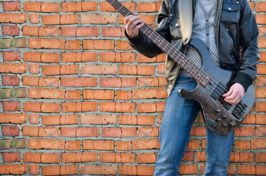 Adam elektro gitar arka plan tuğla duvar üzerinde çalış.