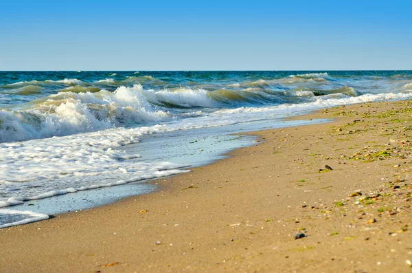 Las olas del mar lavan la playa contra un cielo azul — Foto de Stock