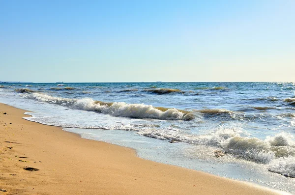 Sea waves wash the beach against a blue sky — Stock Photo, Image