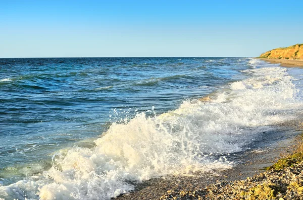 Морські хвилі миють пляж на тлі блакитного неба — стокове фото
