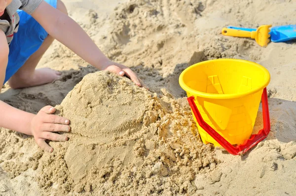 Kleine jongen spelen op het strand in het zand. Kind beeldhouwt cijfers uit het zand. Activiteiten in de zomer op de zee. Rechtenvrije Stockfoto's
