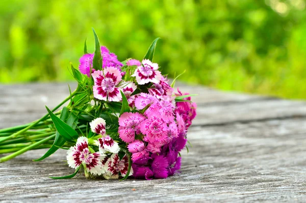 Bouquet of small carnations on a wooden background — Stock Photo, Image