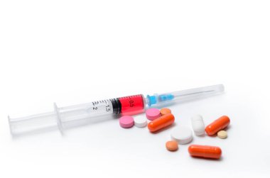 Beyaz arka planda şırınga, aşı ve haplar.