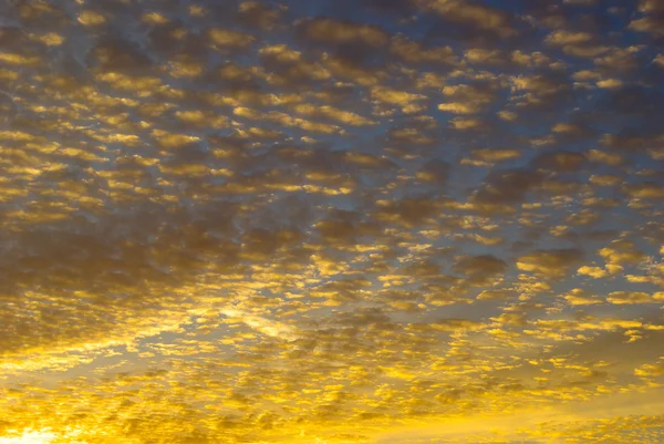 Gökyüzündeki bulutların arasında gün batımının altın ışıkları — Stok fotoğraf