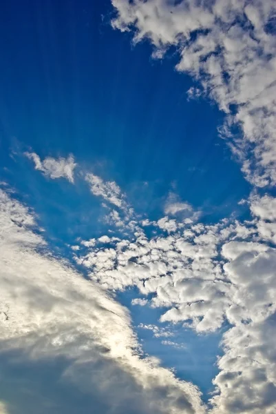 Luz del sol entre las nubes en el cielo azul — Foto de Stock