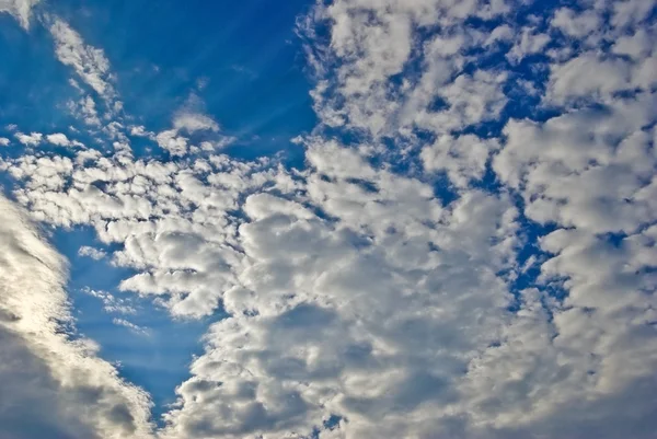 Luz del sol entre las nubes en el cielo azul — Foto de Stock
