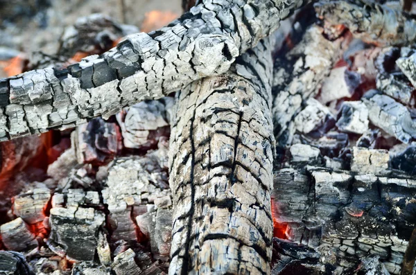Madera carbonizada ardiendo en el resplandor del fuego, primer plano — Foto de Stock